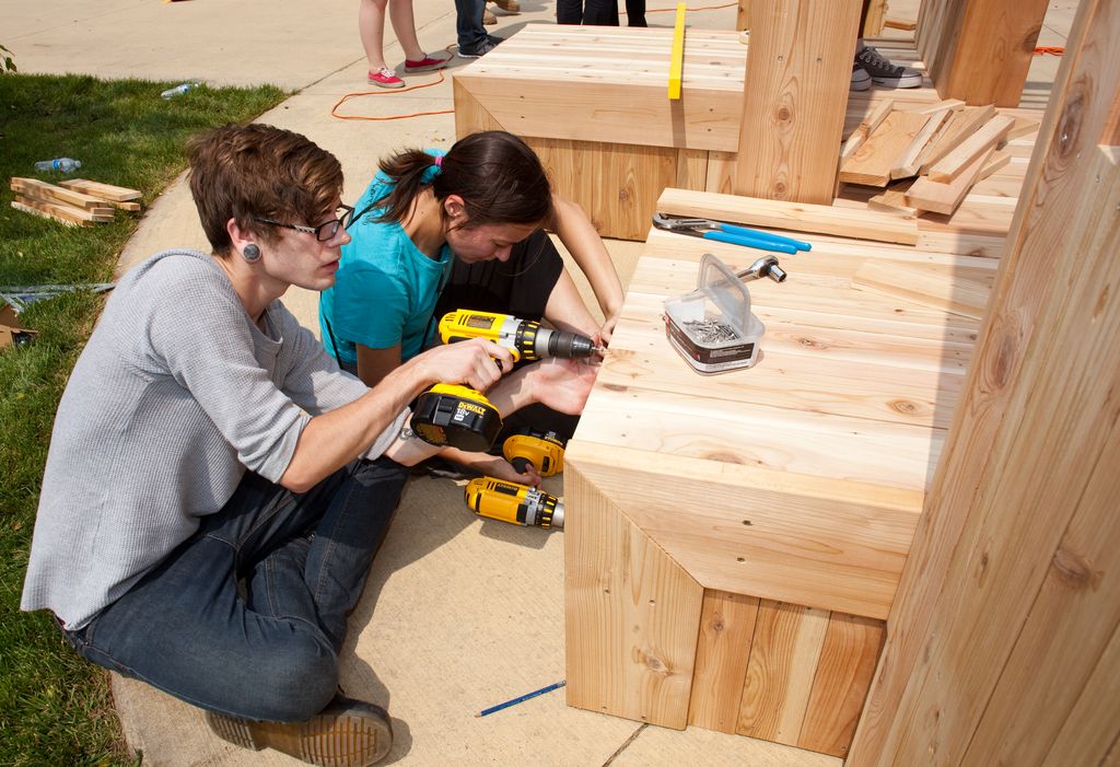 Two people building a cedar planter box with a cordless drill