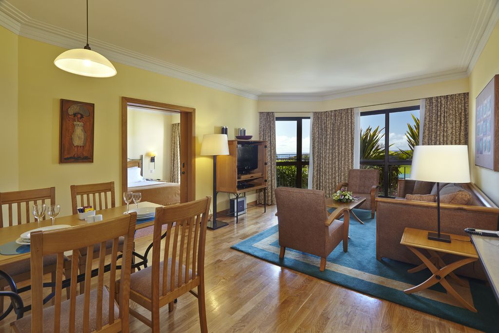 A bright living and dining room with wide windows and wooden floors